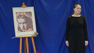 12.	Młoda dziewczyna w ciemnym stroju, z lewej strony portret.