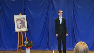 13.	Młody chłopak w ciemnym garniturze, z lewej strony portret.