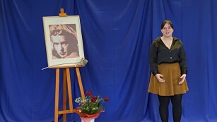 6.	Młoda dziewczyna w czarnej bluzce i brązowej spódnicy, z lewej strony portret.