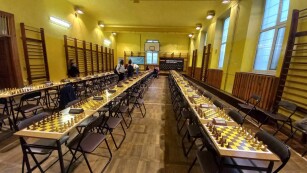 Trzy rzędy stolków, na których rozłożono plansze do gry w szachy