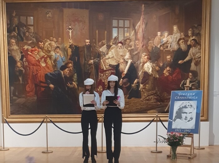 Dwie młode dziewczyny w czapkach Arciszanek na tle obrazu Unia lubelska Jana Matejki