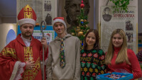 Mikołaj, chłopak w czapce mikołaja i dwie dziewczyny w strojach mikołajkowych