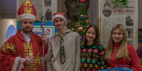 Mikołaj, chłopak w czapce mikołaja i dwie dziewczyny w strojach mikołajkowych