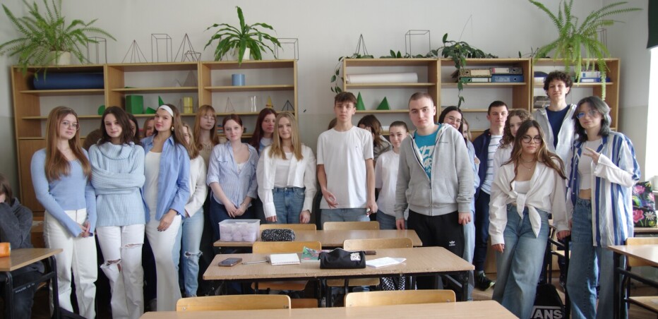 Grupa uczniów w biało-niebieskich strojach w sali lekcyjnej